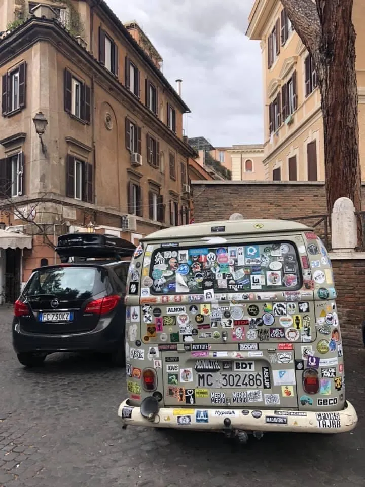Image of a buggy Volkswagen van from behind with a bunch of stickers on it in Rome
